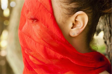 A young woman with a red see-through sheer veil across her face. Stock Photo - Premium Royalty-Free, Code: 6118-07521799