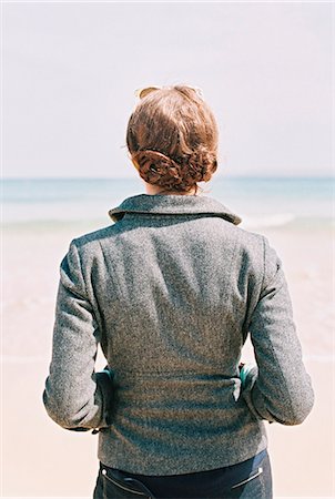 simsearch:6118-08842119,k - A woman in a grey jacket looking out over a beach and the sea. Stock Photo - Premium Royalty-Free, Code: 6118-07762631