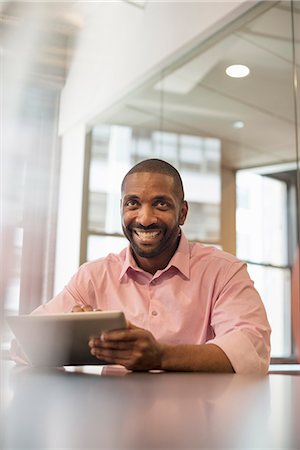 small business and tablet computer - Office life. A man seated at a desk using a laptop computer. Stock Photo - Premium Royalty-Free, Code: 6118-07769488