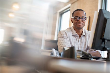 people and computers - Office life. A man seated at a desk using a computer. Stock Photo - Premium Royalty-Free, Code: 6118-07769493