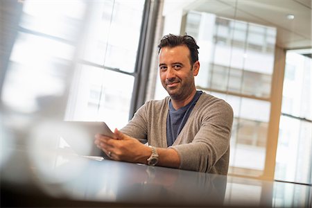 Office life. A man seated at a desk using a digital tablet. Foto de stock - Sin royalties Premium, Código: 6118-07769490