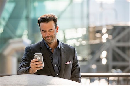 A man seated on a bench checking his smart phone. Photographie de stock - Premium Libres de Droits, Code: 6118-07769499