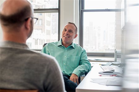 simsearch:6118-07769527,k - Two men seated in a light airy office environment, talking. Photographie de stock - Premium Libres de Droits, Code: 6118-07769508