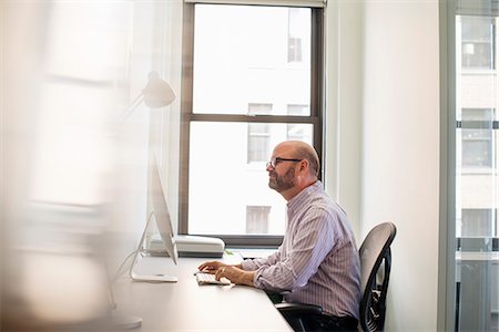 entrepreneur in office - A businessman seated at his desk working at a computer. Stock Photo - Premium Royalty-Free, Code: 6118-07769520