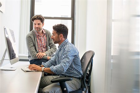 partenaire (affaires) - Two business colleagues in an office talking and referring to a computer screen. Photographie de stock - Premium Libres de Droits, Code: 6118-07769521