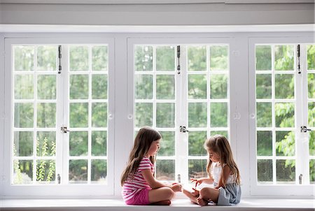 Two girls sitting indoors cross legged. Photographie de stock - Premium Libres de Droits, Code: 6118-07769608