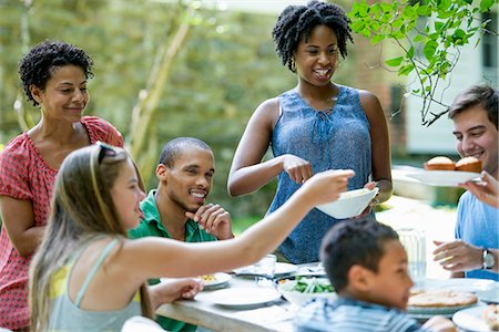 simsearch:6118-07966884,k - A family gathering, men women and children around a table in a garden in summer. Stock Photo - Premium Royalty-Free, Code: 6118-07769621