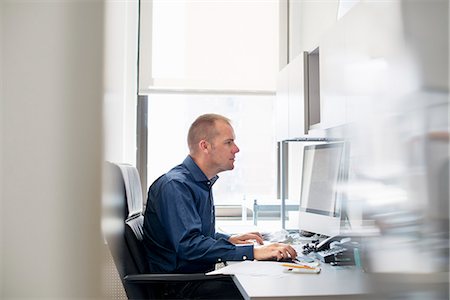 simsearch:6118-07781630,k - A man working in an office at a desk using a computer mouse. Focusing on a task. Fotografie stock - Premium Royalty-Free, Codice: 6118-07781647