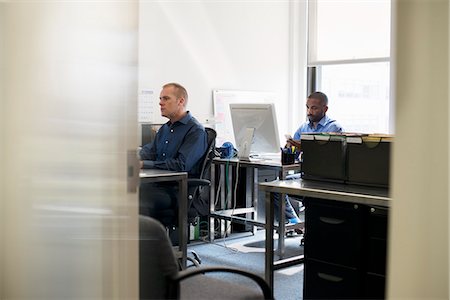 Two men working in an office, using computers. Stock Photo - Premium Royalty-Free, Code: 6118-07781637