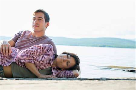 A couple relaxing, lying on a wooden jetty by a lake in summer. Stock Photo - Premium Royalty-Free, Code: 6118-07781762