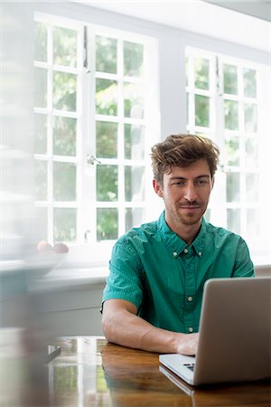 simsearch:6118-07781767,k - A man seated at a table using a laptop. Working from home. Stock Photo - Premium Royalty-Free, Code: 6118-07781768