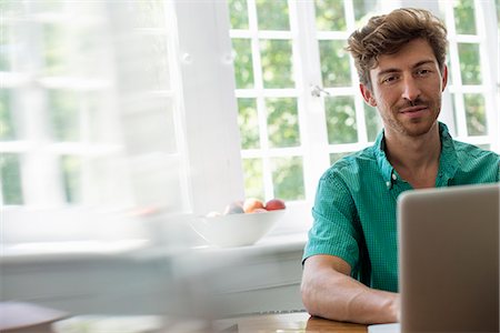 enfoque selectivo - A man seated at a table using a laptop. Working from home. Photographie de stock - Premium Libres de Droits, Code: 6118-07781769