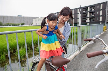 simsearch:6118-09079313,k - A mother lifting her daughter onto a bicycle. Stock Photo - Premium Royalty-Free, Code: 6118-07781793