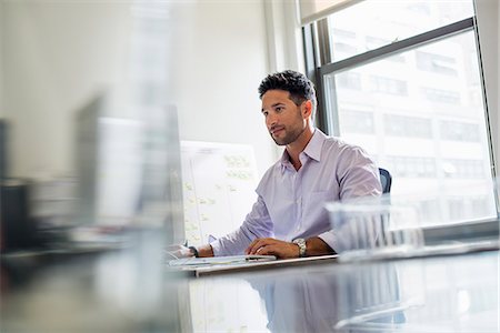 people sitting on desk - Office life. A man working alone in an office. Stock Photo - Premium Royalty-Free, Code: 6118-07781706