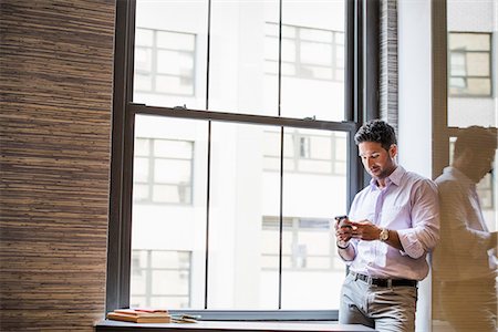 Office life. A man in an office checking his smart phone. Stockbilder - Premium RF Lizenzfrei, Bildnummer: 6118-07781714