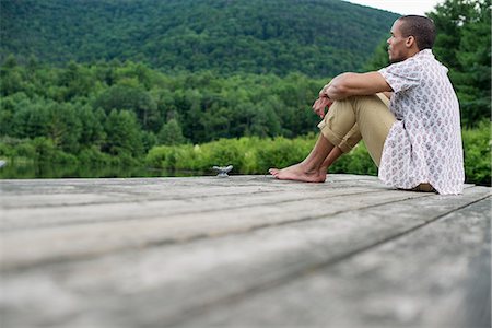 relaxing dock - A man sitting on a wooden pier by a lake in summer Stock Photo - Premium Royalty-Free, Code: 6118-07781737