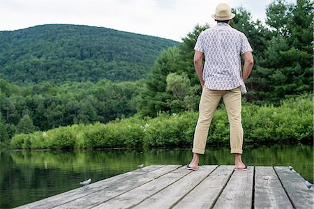 photographic (pertaining to the discipline of photography) - A man standing on a wooden pier overlooking a calm lake. Stock Photo - Premium Royalty-Free, Code: 6118-07781735