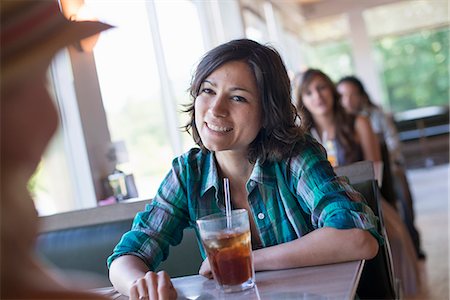 A woman seated at a diner looking at her companion. A long cool drink with a straw. Photographie de stock - Premium Libres de Droits, Code: 6118-07781806