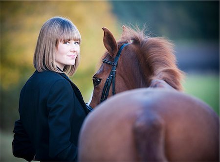 riding tack - A woman leading a bay horse by the bridle. Stock Photo - Premium Royalty-Free, Code: 6118-07731697