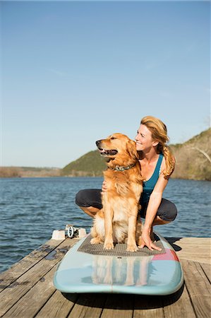 A woman and a retriever dog on a paddleboard on the jetty. Stock Photo - Premium Royalty-Free, Code: 6118-07731792