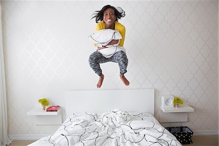 A young girl jumping high in the air above her bed. Foto de stock - Sin royalties Premium, Código: 6118-07731735