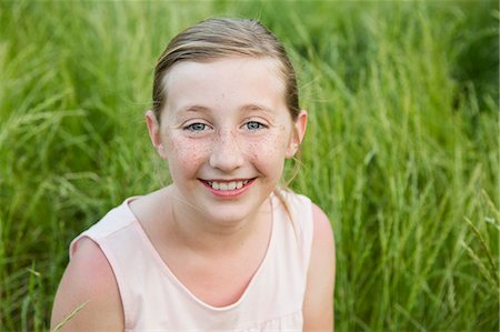 simsearch:6118-07731949,k - A young girl smiling, sitting on the ground. Photographie de stock - Premium Libres de Droits, Code: 6118-07731973