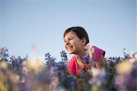 A girl sitting in a field of tall grass and blue wild flowers. Stock Photo - Premium Royalty-Free, Code: 6118-07731985