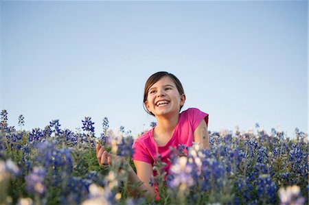 A young girl sitting in a field of wild flowers, laughing. Photographie de stock - Premium Libres de Droits, Code: 6118-07731986