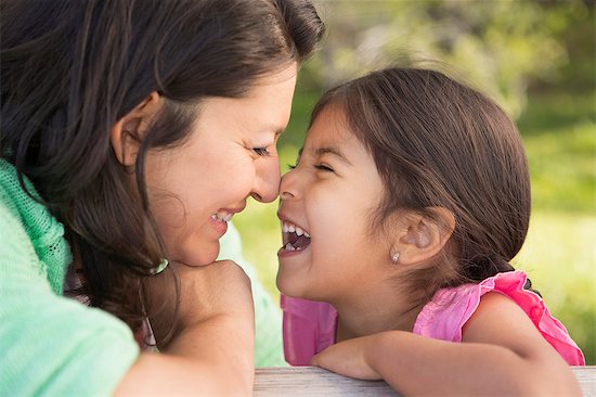 A mother in the park with her daughter, laughing and kissing each other. Stock Photo - Premium Royalty-Free, Image code: 6118-07732063