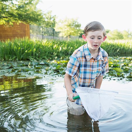 exploring children - A young boy standing thigh deep in water, with a fishing net. Stock Photo - Premium Royalty-Free, Code: 6118-07732017