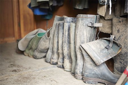 simsearch:693-03565357,k - Several pairs of muddy wellington boots on a stone floor. Foto de stock - Royalty Free Premium, Número: 6118-07808925