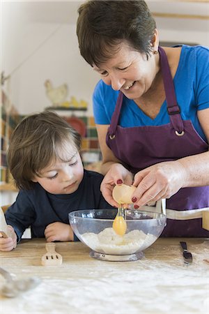 A woman and a child cooking at a kitchen table, making fairy cakes. Stock Photo - Premium Royalty-Free, Code: 6118-07808933