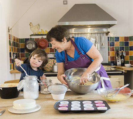 A woman and a child cooking at a kitchen table, making fairy cakes. Foto de stock - Sin royalties Premium, Código: 6118-07808937