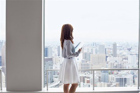 regarder par la fenêtre - A working woman in an office building. Photographie de stock - Premium Libres de Droits, Code: 6118-07813220