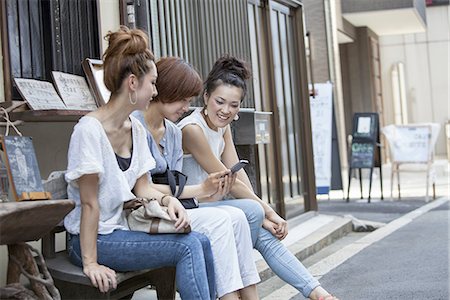 simsearch:6118-07521727,k - Three women sitting outdoors, looking at cellphone. Stockbilder - Premium RF Lizenzfrei, Bildnummer: 6118-07813303