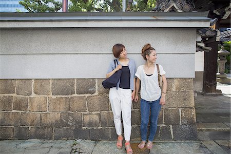simsearch:6118-07813281,k - Two women standing outdoors, leaning against a wall. Stock Photo - Premium Royalty-Free, Code: 6118-07813300