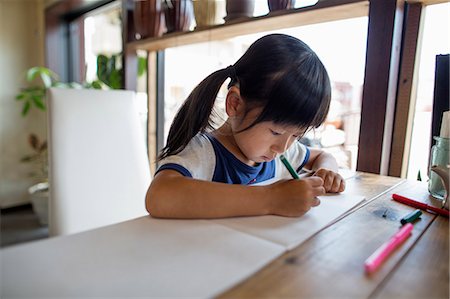 Girl with pigtails sitting at a table, drawing with felt tip pens. Foto de stock - Sin royalties Premium, Código: 6118-07813314