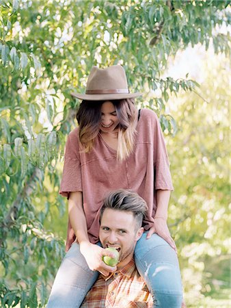 An apple orchard in Utah. man carrying a woman on his shoulders, eating an apple. Stock Photo - Premium Royalty-Free, Code: 6118-07944784