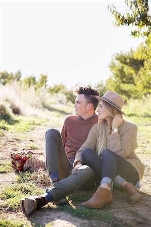 An apple orchard in Utah. Couple sitting on the ground, a basket of apples. Stock Photo - Premium Royalty-Free, Code: 6118-07944795