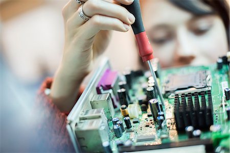 A woman using an electronic screwdriver on a computer circuitboard. Stock Photo - Premium Royalty-Free, Code: 6118-07966860