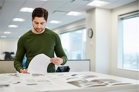 A man in an office checking proofs of printed pages. Stock Photo - Premium Royalty-Free, Code: 6118-08066758