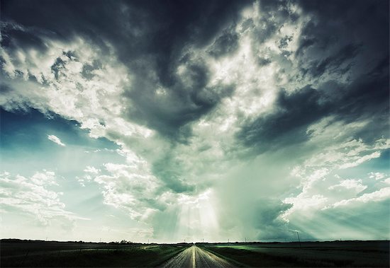 A road reaching towards the horizon, under a dramatic sky. Stock Photo - Premium Royalty-Free, Image code: 6118-08066762