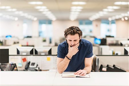 simsearch:622-08657638,k - A man leaning on  his elbow and looking at an open book on an office desk. Stock Photo - Premium Royalty-Free, Code: 6118-08066730