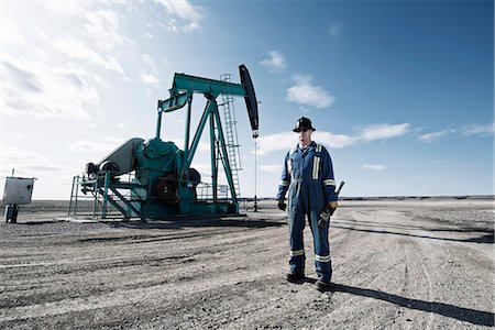 A man in overalls and a hard hat with a large wrench working at an oil extraction site. Foto de stock - Sin royalties Premium, Código: 6118-08081890