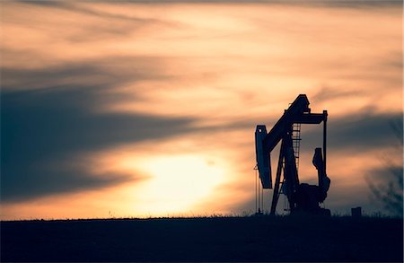 A pumpjack at an oil drilling site at sunset. Stock Photo - Premium Royalty-Free, Code: 6118-08088546