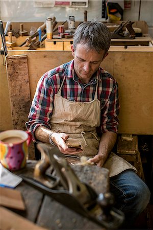 An antique furniture restorer in his workshop, using a smart phone. Stockbilder - Premium RF Lizenzfrei, Bildnummer: 6118-08088603