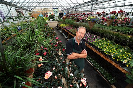 simsearch:6118-08842102,k - A man standing in a greenhouse with shelves of plants. Stock Photo - Premium Royalty-Free, Code: 6118-08088616