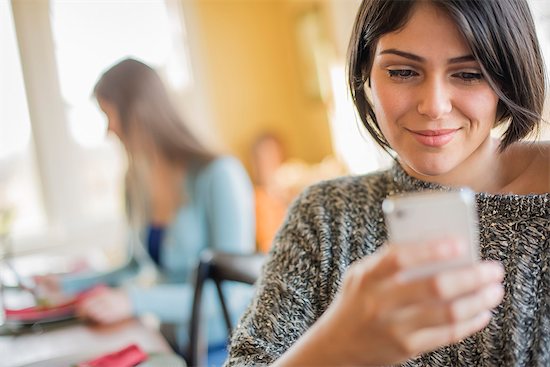 A woman checking her smart phone. Stock Photo - Premium Royalty-Free, Image code: 6118-08001551