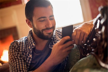 A man checking his cell phone and smiling. Photographie de stock - Premium Libres de Droits, Code: 6118-08001572