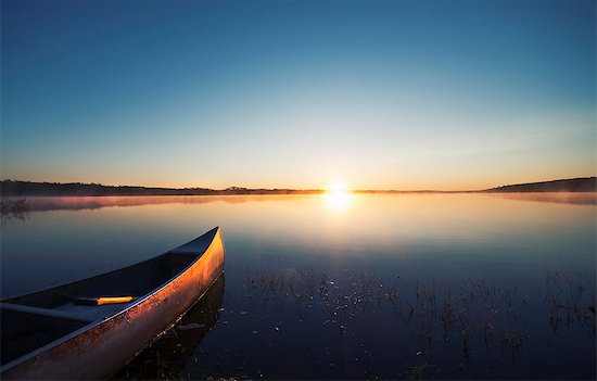 A canoe on a flat calm lake at sunset. Stock Photo - Premium Royalty-Free, Image code: 6118-08023774